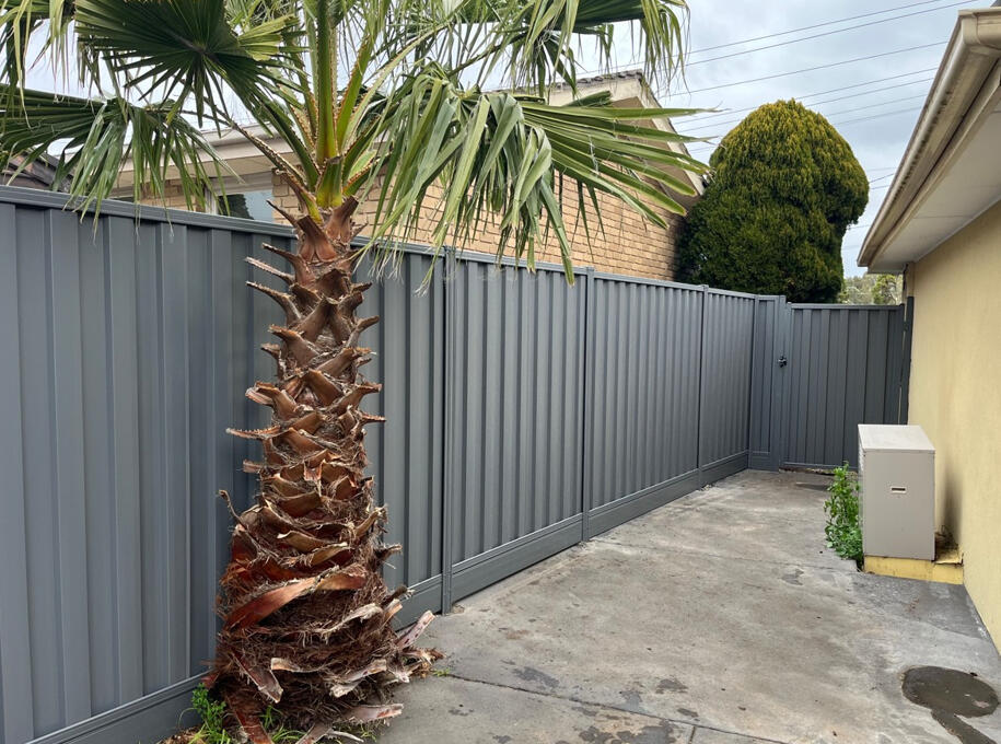 Basalt Colorbond boundary fence with aluminium sleepers and matching gate. 1.95m high Colorbond privacy fence with aluminium sleepers and matching gate completed for a shared boundary in Noble Park North.