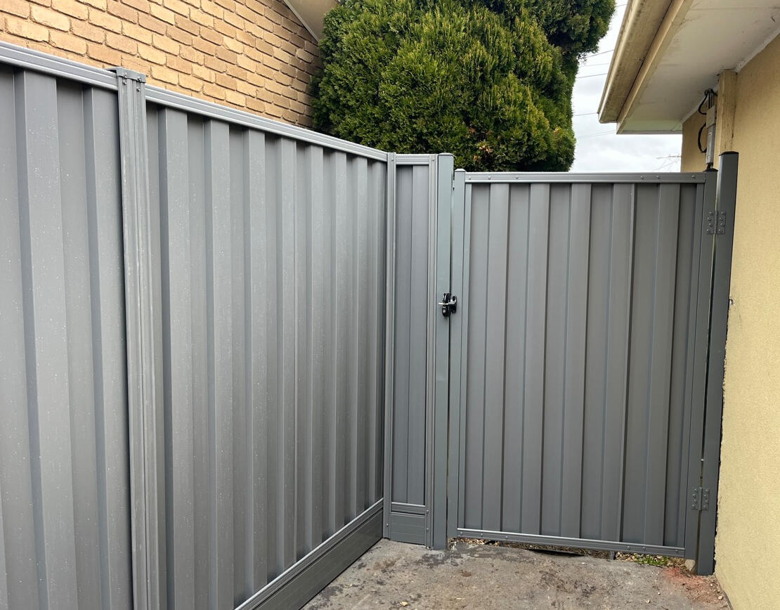 Basalt Colorbond pedestrian side gate completed in Noble Park to match existing privacy fencing and aluminium sleepers for improved backyard access and security.