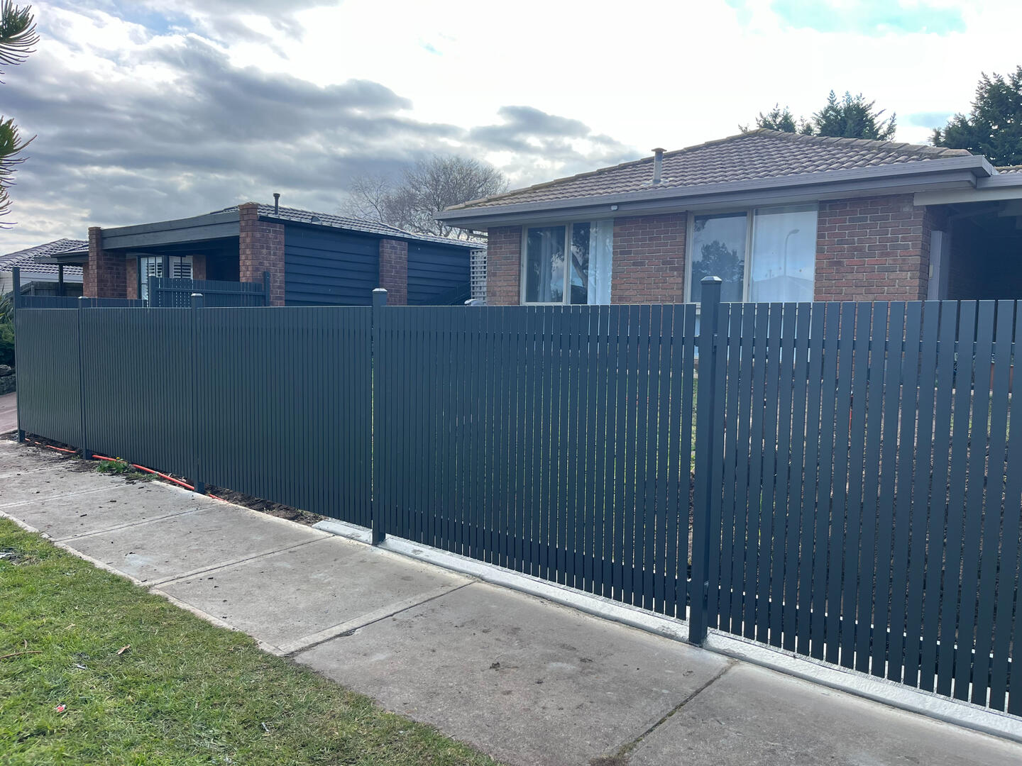 Monument aluminium slat front fence with welded vertical slats for added privacy and security. Custom Monument aluminium slat front boundary fence completed in Cranbourne North featuring welded vertical slats for improved privacy, pet security and modern street appeal.