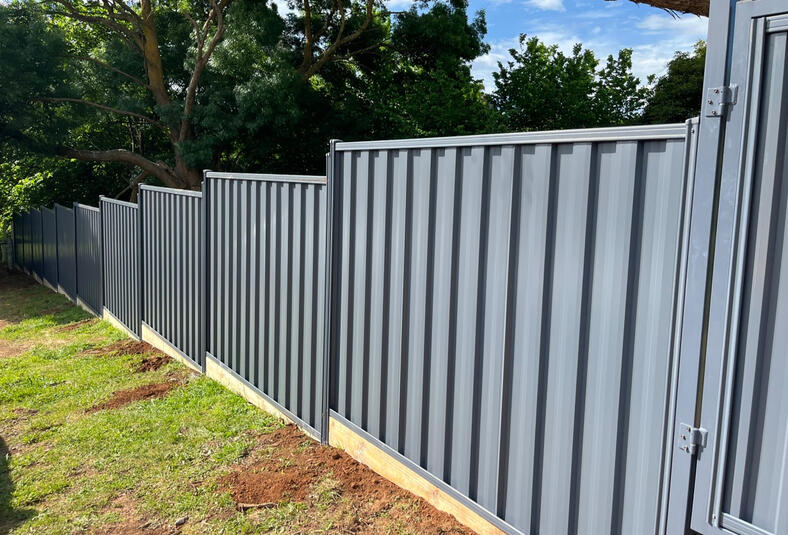 Ironstone Colorbond fencing with timber sleepers installed across a large sloping acreage property in Drouin. Ironstone Colorbond acreage fence with timber sleepers installed on sloping land in Drouin.
